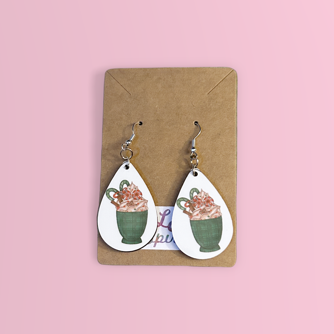 green plaid coffee cup with Christmas candy teardrop earrings on pink background