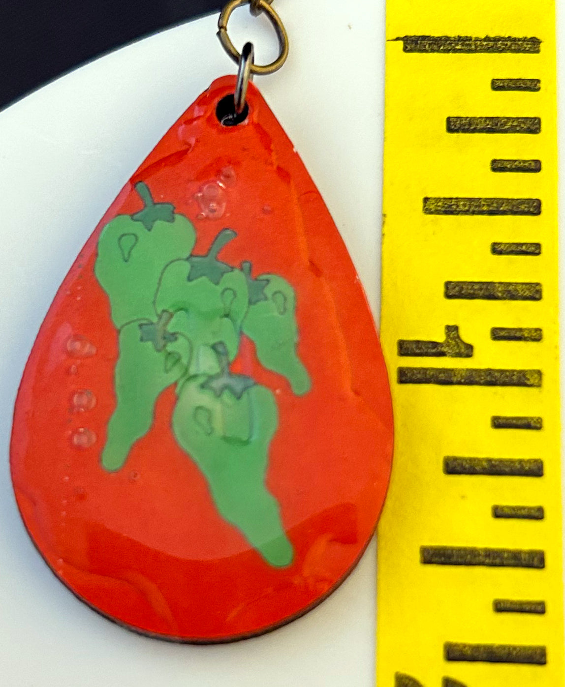 teardrop earrings with green chili on red background