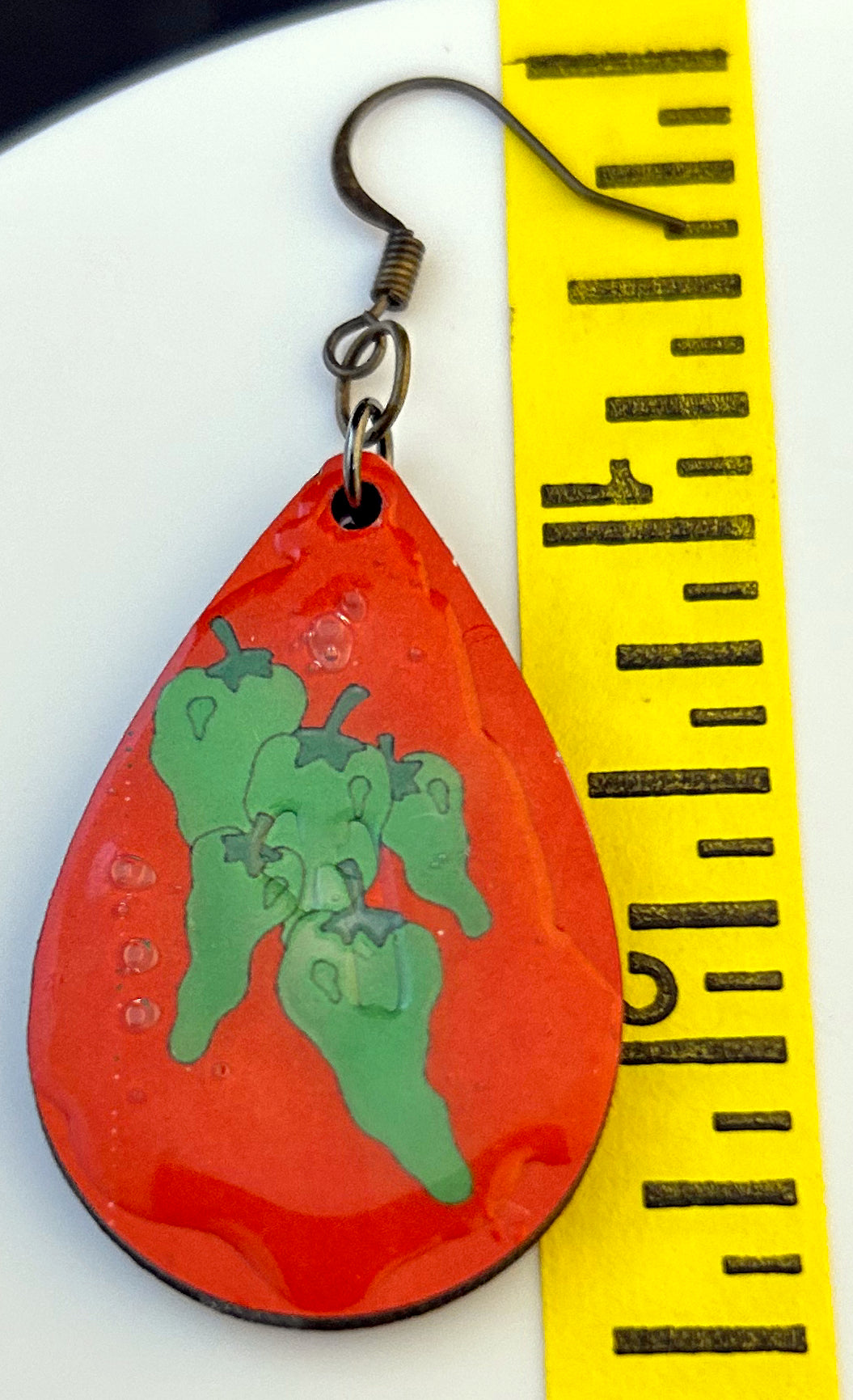 teardrop earrings with green chili on ed background
